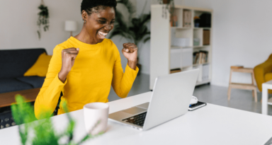 multiracial woman celebrating good news on laptop